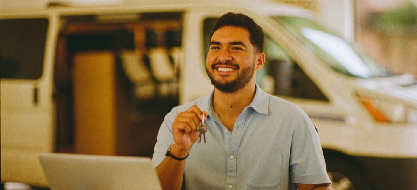 Empresario sonriente con las llaves de un vehículo de trabajo